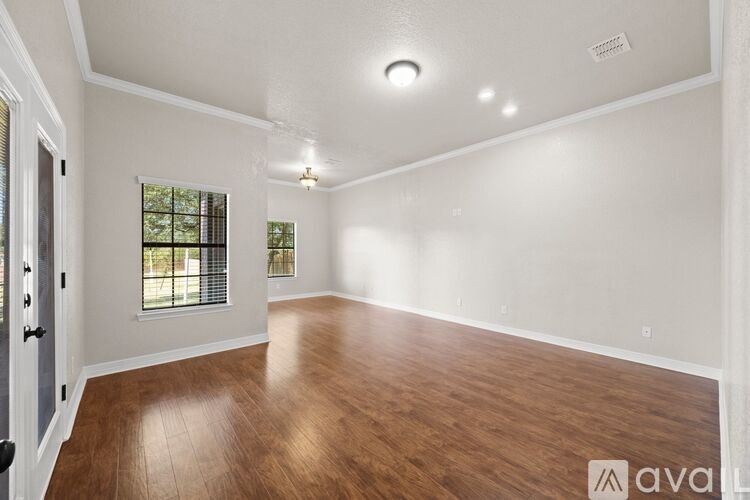 A spacious room with wooden floors and white walls.