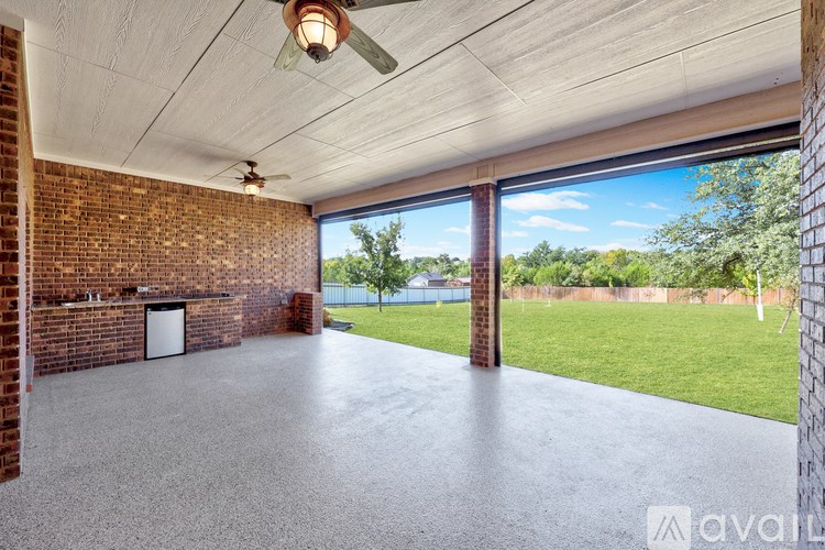 A room with a ceiling fan and a large window overlooking a green lawn.