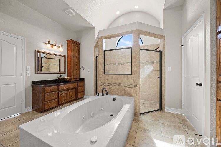 A large, luxurious bathroom with a bathtub, vanity, and a walk-in shower.