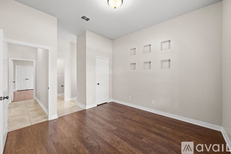 A spacious room with wooden flooring and white walls.