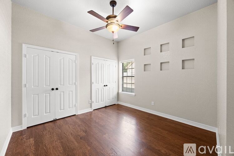 A room with a ceiling fan and wooden floors.
