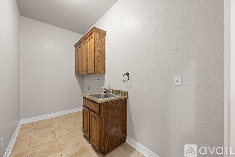 A kitchen area with a sink and wooden cabinets.