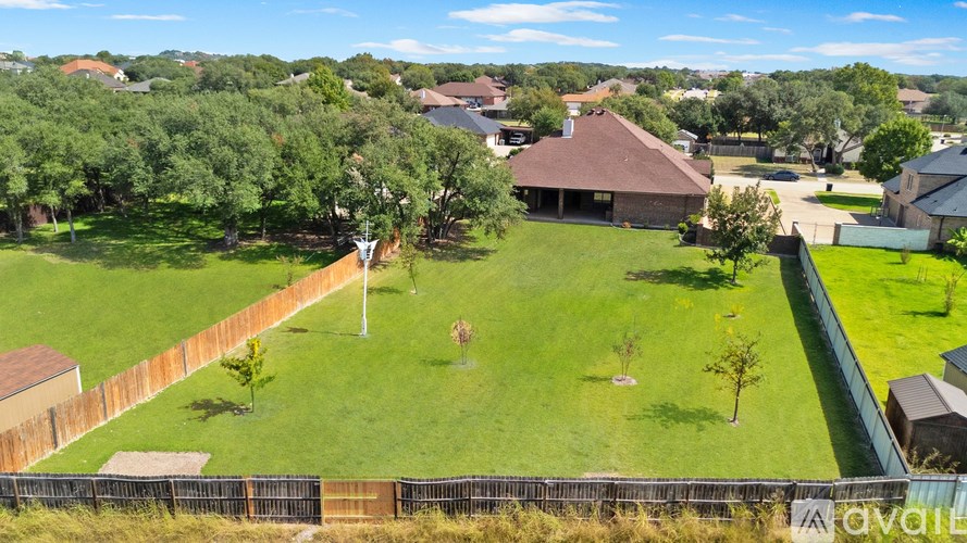 A large grassy yard with a house and a fence.