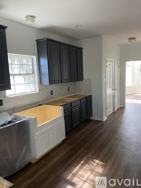 A kitchen with black cabinets and a wooden floor.