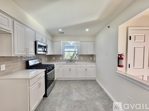 A kitchen with white cabinets and a black stove top oven.