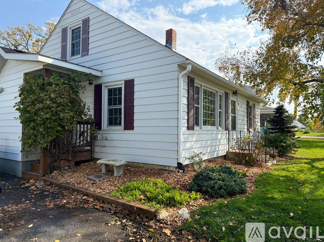 A white house with a red window and a brown roof.