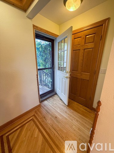 A hallway with a wooden floor and a white door.