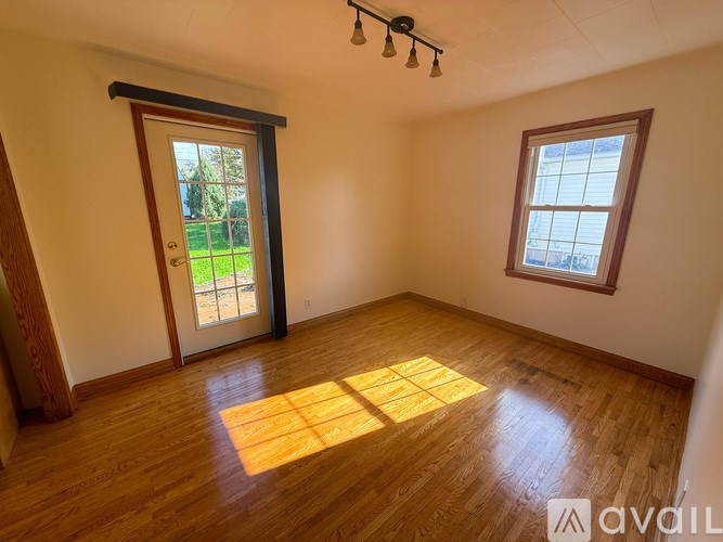 A room with wooden floors and a window on the right side.