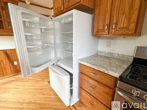 A kitchen with a white refrigerator and wooden cabinets.