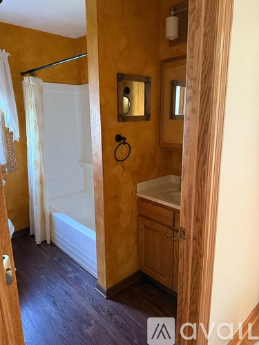 A bathroom with a white tub and a wooden door.