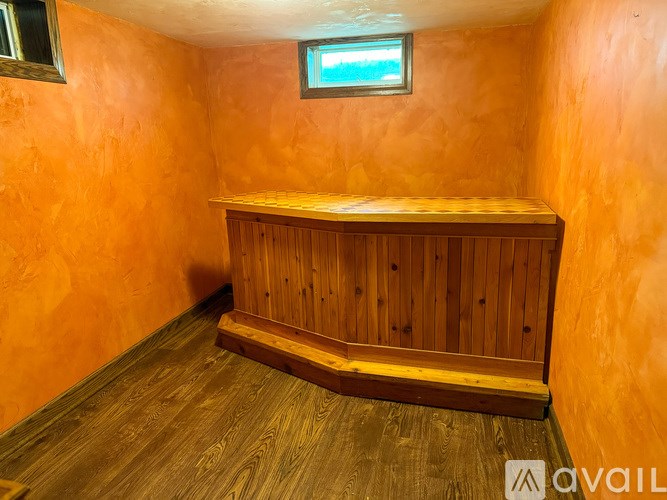 A wooden bench is placed in the middle of a room with orange walls.