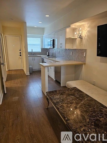 A modern kitchen with a marble countertop and a television mounted on the wall.