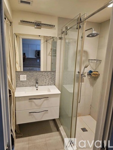 A bathroom with a white sink and a glass shower stall.