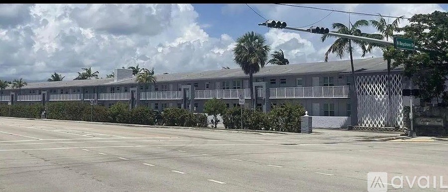 A street view of a building with a fence and palm trees.