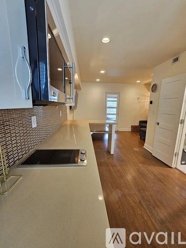 A kitchen with a stainless steel dishwasher and wooden flooring.