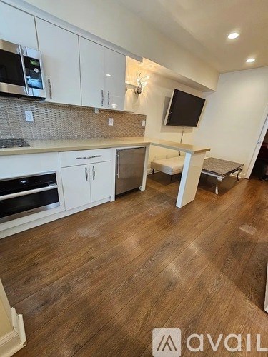 A kitchen with white cabinets and a wooden floor.