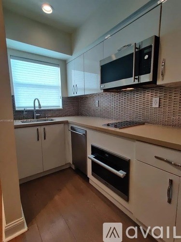 A kitchen with white cabinets and a black microwave above the stove.