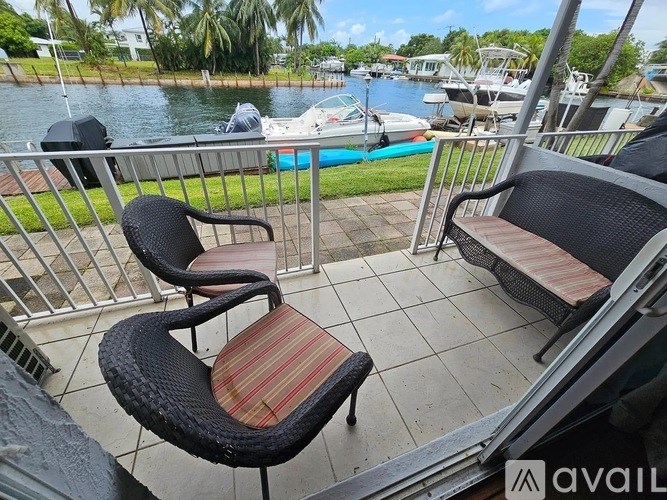 A balcony with two chairs and a bench overlooks a body of water with boats.