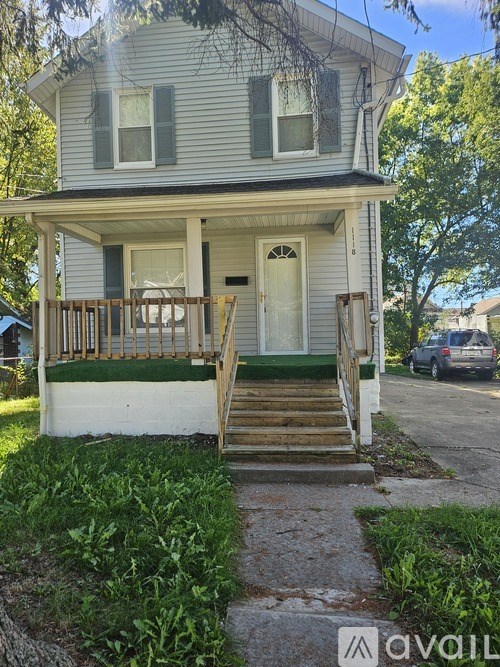 A small house with a porch and stairs leading to the front door.