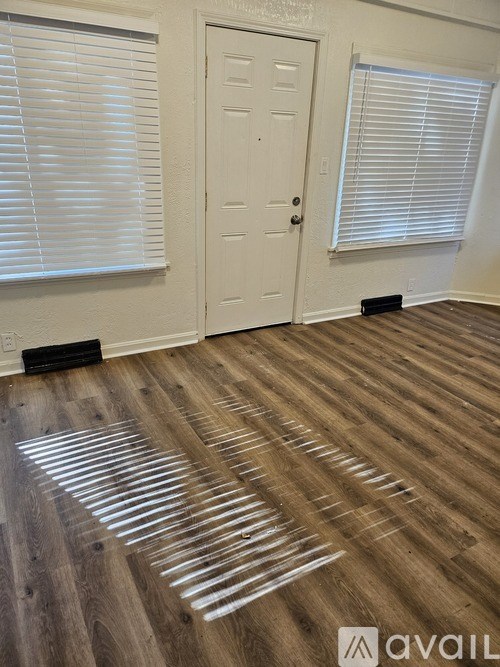 A room with wooden flooring and a white door.