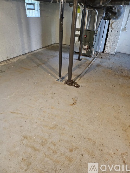 A dirty basement with a metal pole in the middle.
