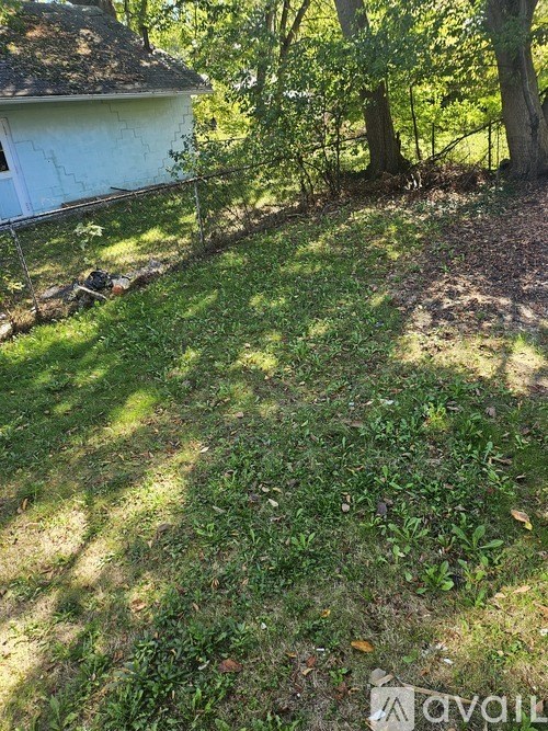 A backyard with a white house and trees.