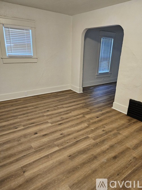 A room with wooden flooring and a window with blinds.