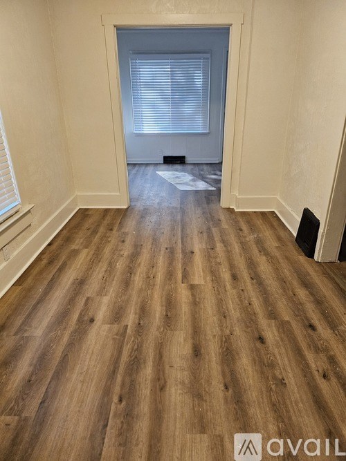 A room with wooden flooring and a window with blinds.