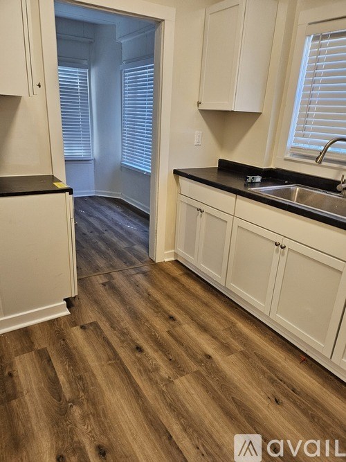A kitchen with white cabinets and a wooden floor.