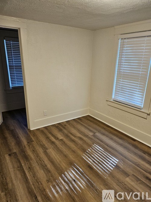 A room with wooden flooring and a window with blinds.
