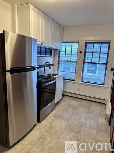 A kitchen with a stainless steel refrigerator and a window.