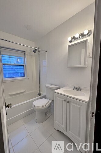 A white bathroom with a toilet, sink, and a window.