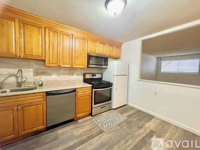 A kitchen with wooden cabinets and a black dishwasher.