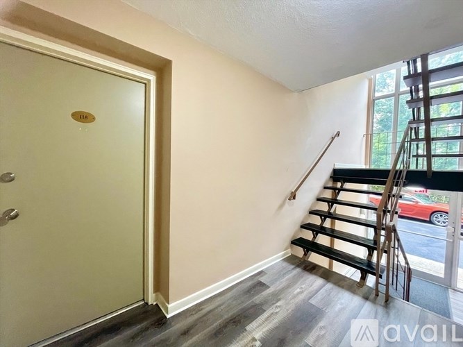 A room with a white door and a staircase leading to the upper floor.