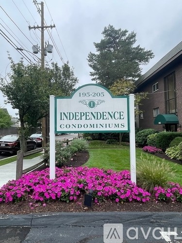 A sign for Independence Condominiums with a flower bed in front.