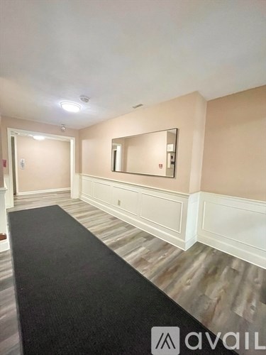 A hallway with a black carpet and wooden flooring.