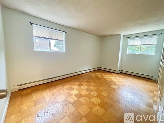 A room with wooden flooring and two windows.