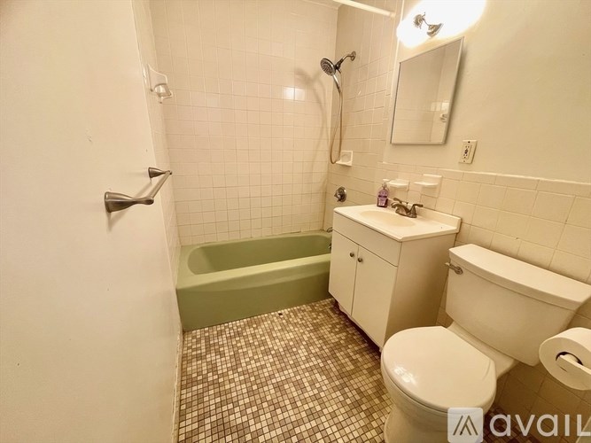 A bathroom with a green tub, white toilet, and sink.