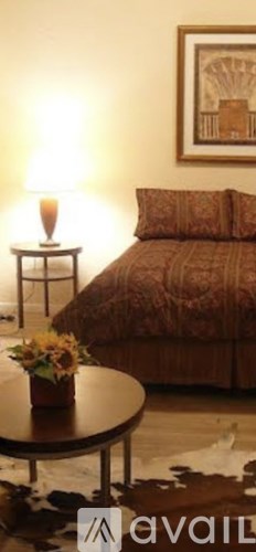 A bedroom with a bed, a table, and a painting on the wall.