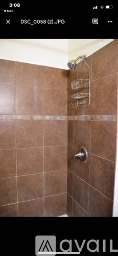 A shower area with brown tiles and a silver shower head.