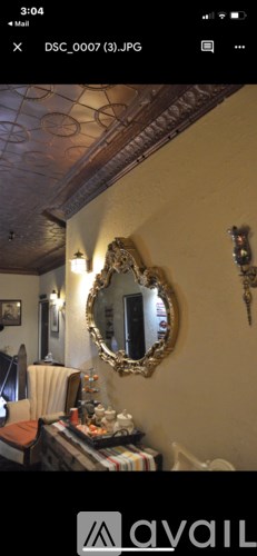 A mirror with a gold frame hangs on a wall above a table with a striped tablecloth.