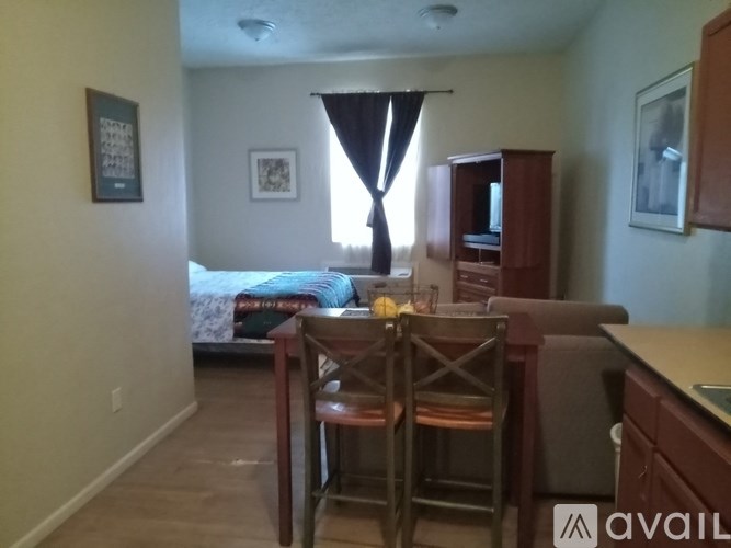 A bedroom with a bed, a chair, and a cabinet.