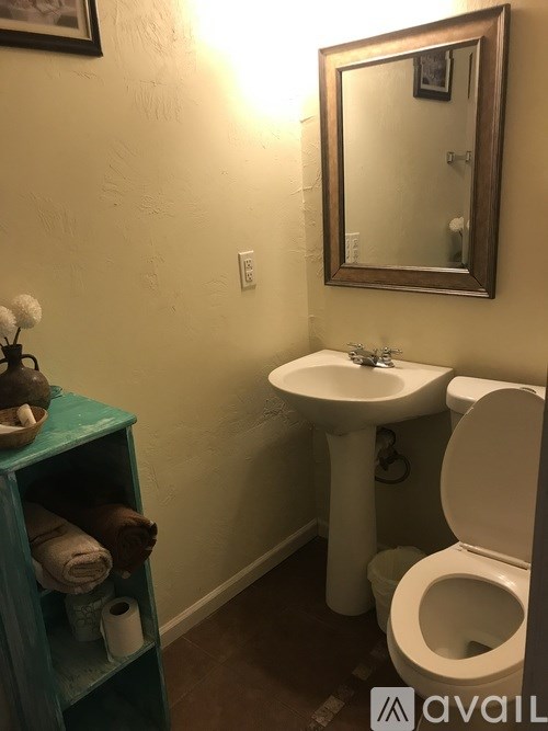 A bathroom with a toilet, sink, and mirror.