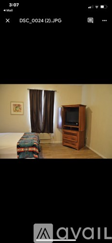 A room with a bed, a curtain, and a wooden cabinet.