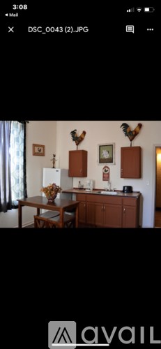 A kitchen with wooden cabinets and a table with a vase of flowers on it.