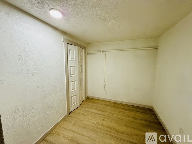 A room with a white door and wooden floor.