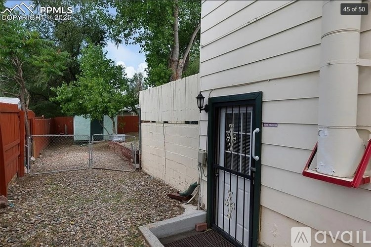 A white house with a black gate and a sign that says "available".