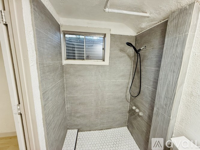A small, white bathroom with a shower and a window.