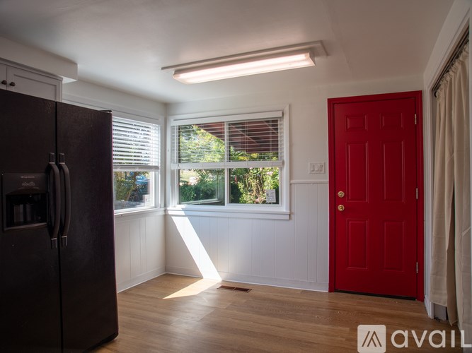 A kitchen with a black fridge and a red door.