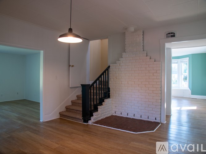 A room with a staircase and a hanging light fixture.